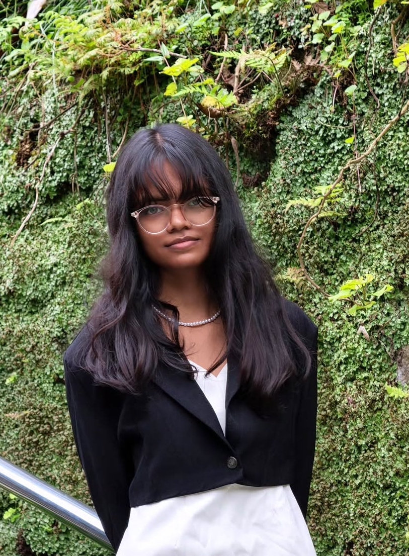 Anvi Goddard in a black blazer and glasses standing outdoors